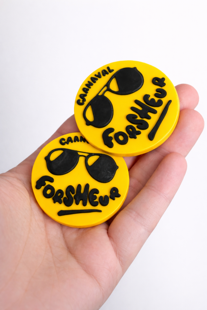 Badge rond jaune Carnaval avec lunettes noires et texte en relief, imprimé en 3D.