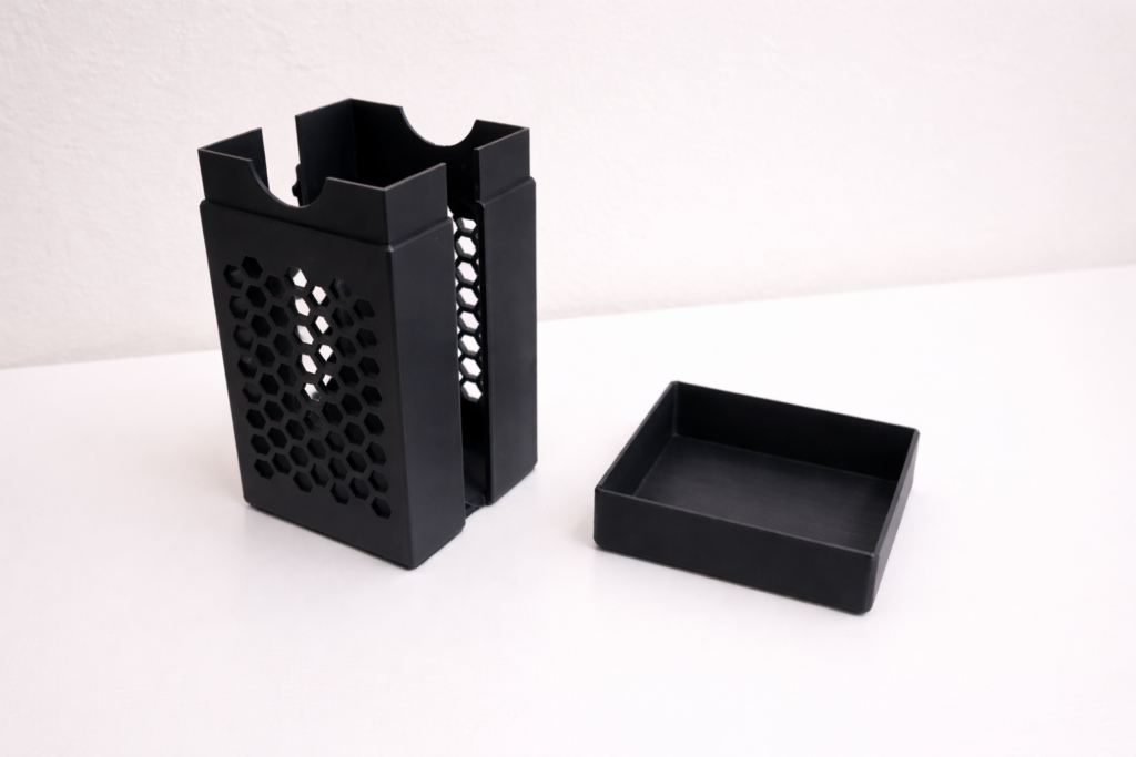 Boîte de rangement noire imprimée en 3D avec structure ajourée hexagonale.